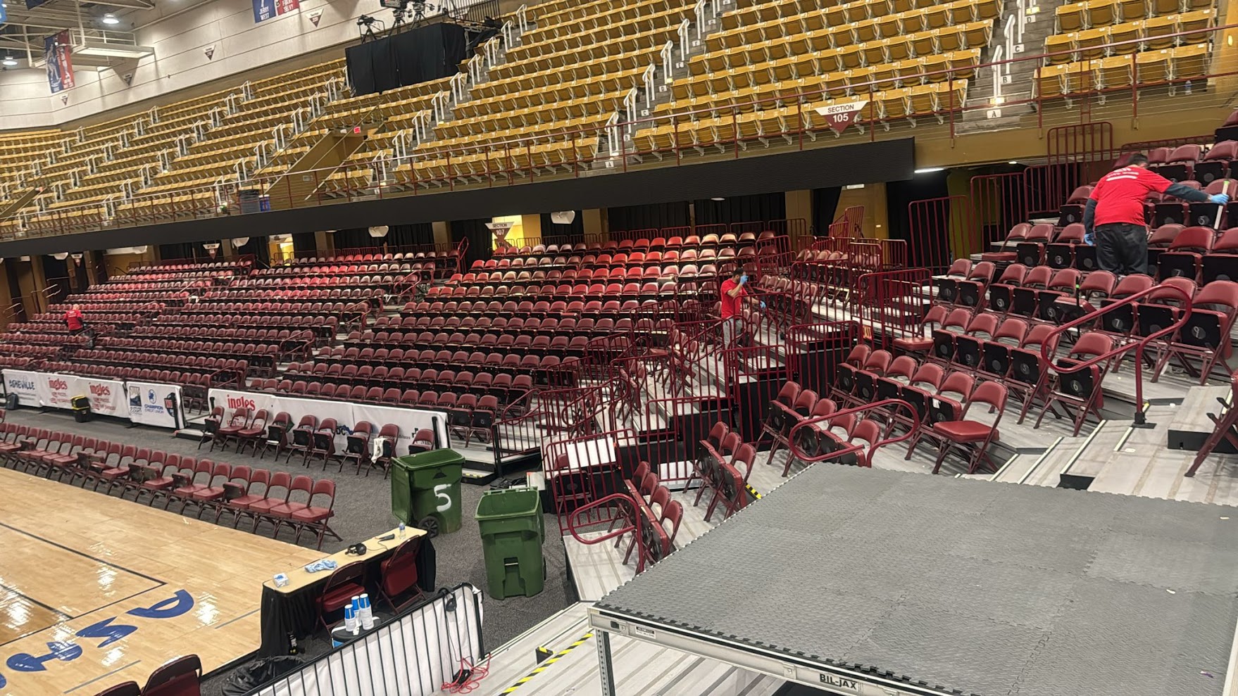 Professional event cleanup team working in large sports arena with systematic waste management